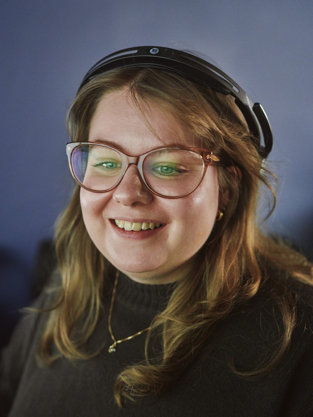 Emilia Nilsson, First line Support på Zendr, med headset och glasögon, ler mot kameran.